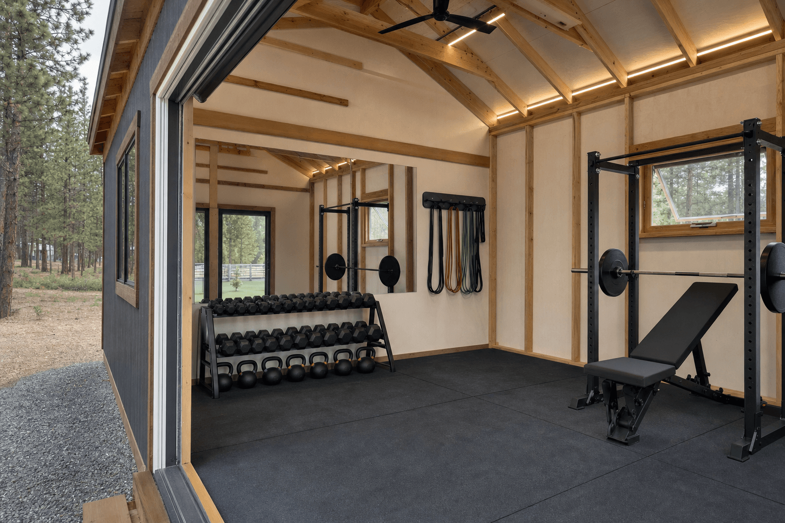 Interior of a home gym shed with a power rack, rubber flooring, mirrors, and a cardio machine