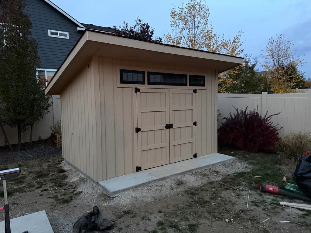 front corner of studio shed with double doors and transom windows on slab