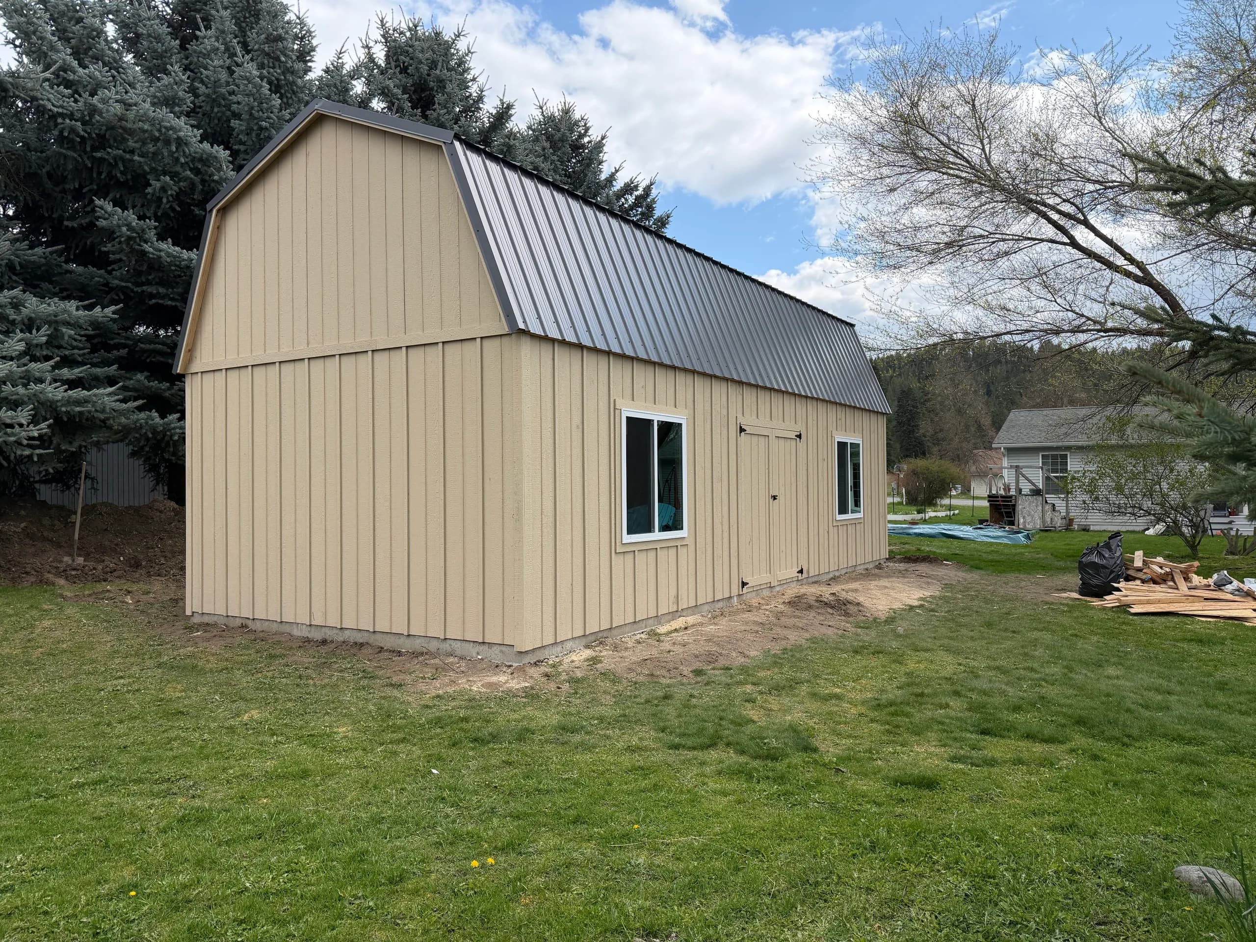 lofted barn storage shed with two windows, metal roof, double doors, board and batt siding